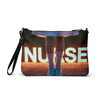 Nurse in Lights crossbody bag, back view: glowing NURSE sign and lace-up shoes printed edge to edge on black faux leather, wrist strap attached