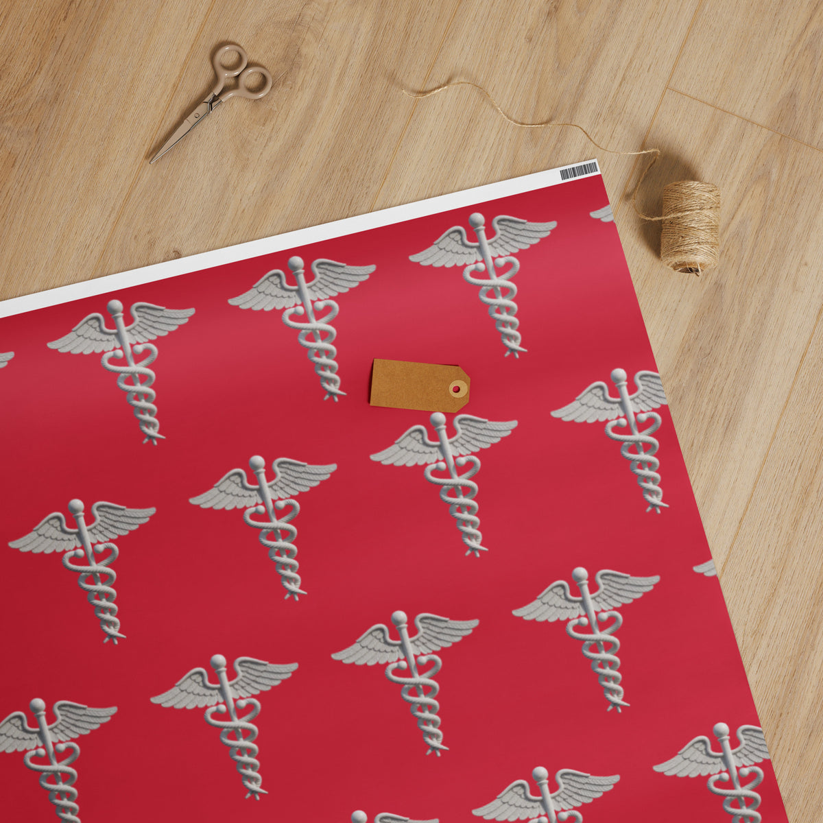 Medical Caduceus Wrapping Paper, caduceus symbols on crimson: white glossy finish, unrolled on a wooden table with scissors, twine and a kraft gift tag
